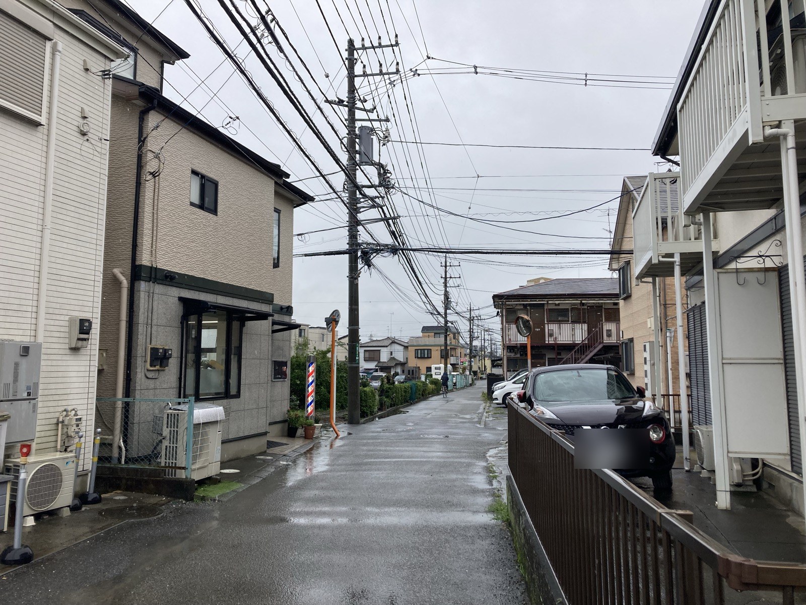 車1台分の幅しかない細い道。床屋のサインポールと道の真ん中に立つ電柱