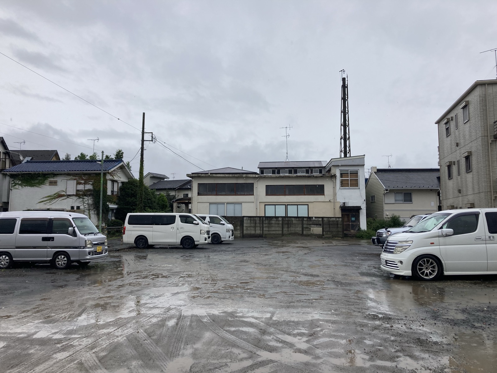 雨の日のしずの湯の駐車場。未舗装で水たまりができている